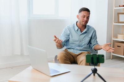 Portrait of young man using laptop at home