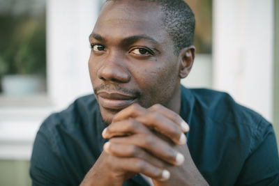 Portrait of confident mid adult man with hands clasped