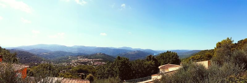 Scenic view of trees and mountains against blue sky