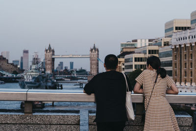 Rear view of people looking at city against sky