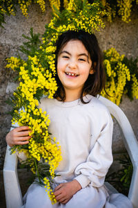 Portrait of young woman sitting on yellow flowers