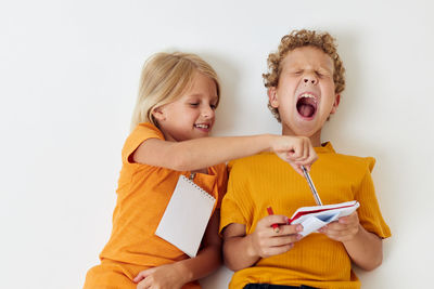 Smiling sibling holding notebook against white background