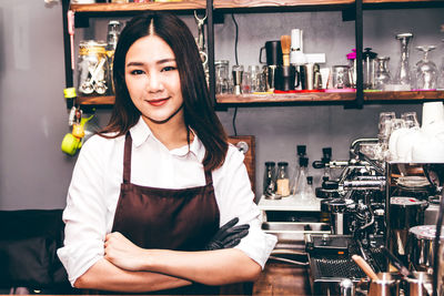 Portrait of female barista with arms crossed standing in kitchen at cafe