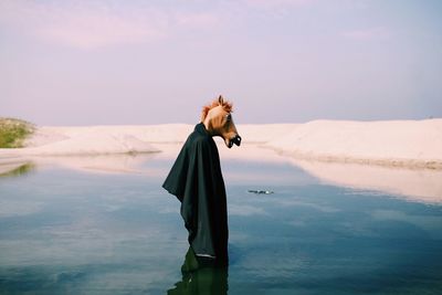 Woman standing in sea against sky
