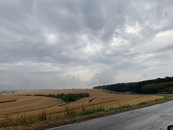 Scenic view of road amidst field against sky