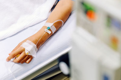 Cropped hand of female patient with iv drip on hand at hospital