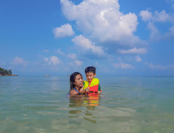 Mother and son in sea against sky