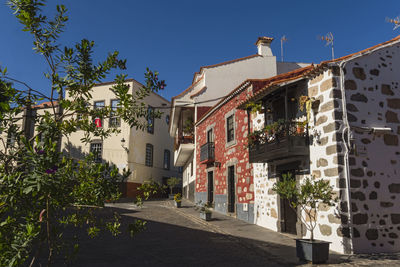 Street amidst buildings in town against clear blue sky