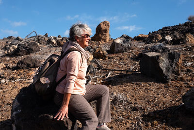 Side view of senior woman sitting on rock