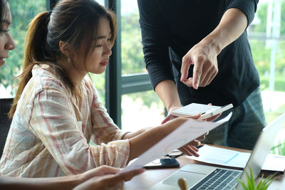 Midsection of woman holding smart phone while sitting on table