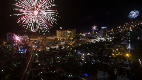 Firework display over illuminated buildings in city at night