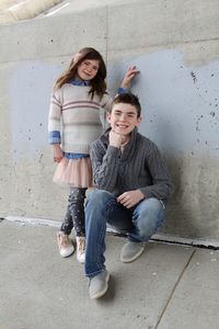 Portrait of smiling siblings against wall