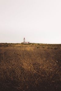 Lighthouse on field against clear sky