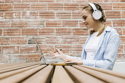 Side view of a young woman leaning against wall