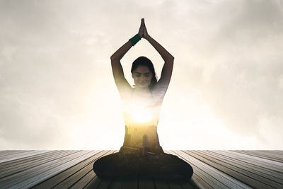Portrait of woman with arms raised standing against sky