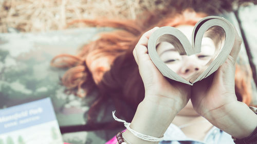 Midsection of woman holding heart shape with text