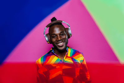 Portrait of smiling young man standing against multi colored background