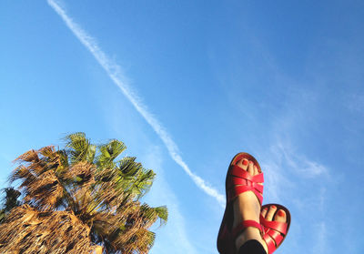 Low angle view of woman with feet up against sky