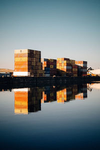 Buildings by river against clear sky