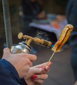 Close-up of hand holding torch melting a cheese stick