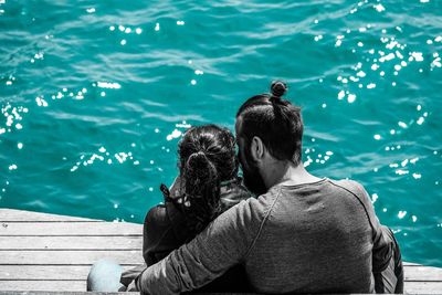 Rear view of couple sitting by sea