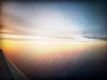 Cropped image of airplane wing over clouds