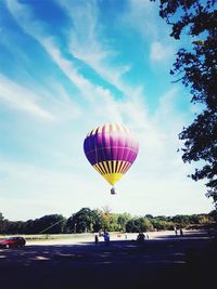 Hot air balloon flying over trees against sky