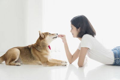 Side view of young woman with cat against white background