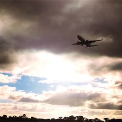 Low angle view of silhouette airplane flying in sky