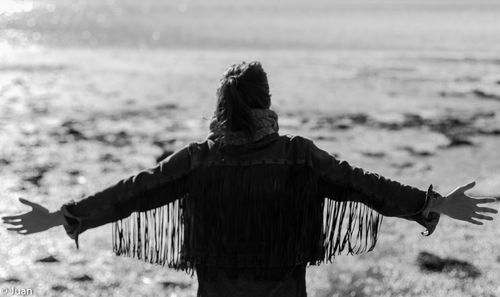 Rear view of woman standing at beach