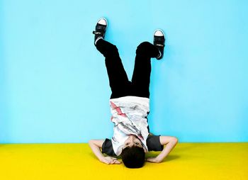 Upside side down image of boy against blue wall