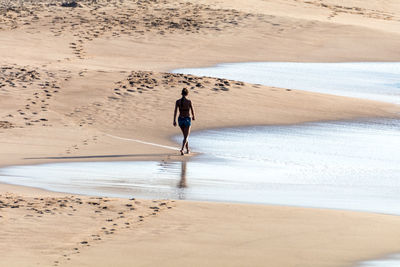 Rear view of woman walking at beach