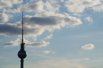 Low angle view of communications tower against cloudy sky