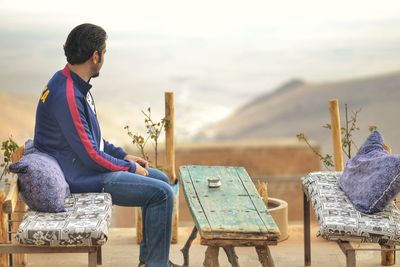 Side view of man sitting on bench