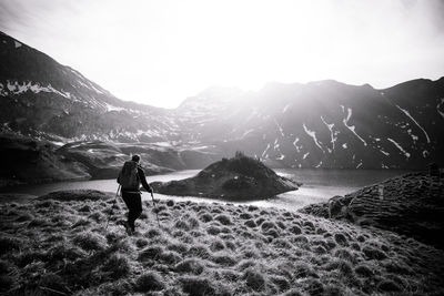 Rear view of woman walking on land against mountain