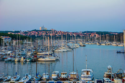 Boats moored in harbor at city against clear sky