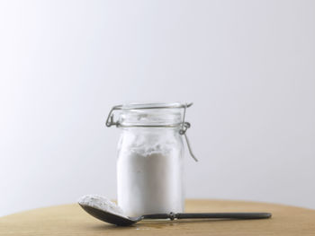 Close-up of glass jar on table against white background