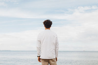 Rear view of man looking at sea against sky