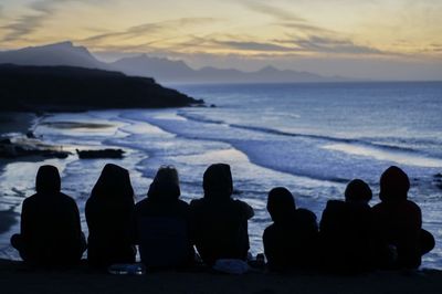 Silhouette people looking at sea against sky