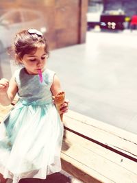 Cute girl looking away while standing on wood