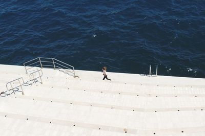 High angle view of a woman jogging on stairs by the river