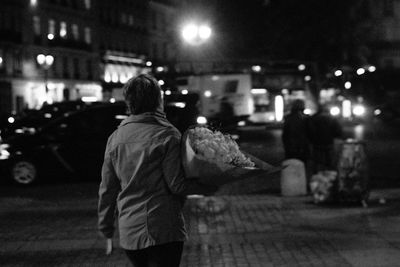 Rear view of man walking on road at night