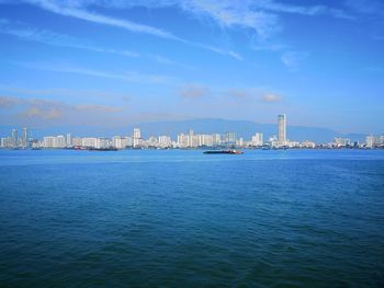 Sea by city against blue sky