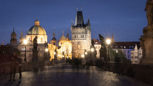 People walking on busy historical charles bridge during late evening, wide shot, prague, czechia