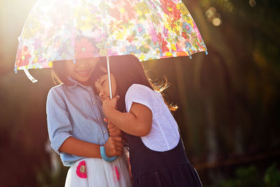 Close-up of sisters with umbrella standing outdoors