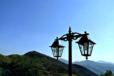 Low angle view of cross on mountain against clear blue sky