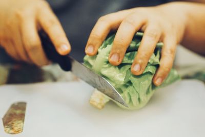 Close-up of person cutting vegetable on table