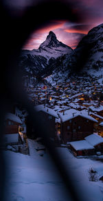 Snow covered townscape by mountains against sky at night during winter
