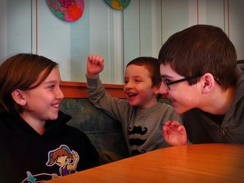 Portrait of happy friends sitting on table