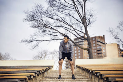 Tired male athlete standing on steps at stadium